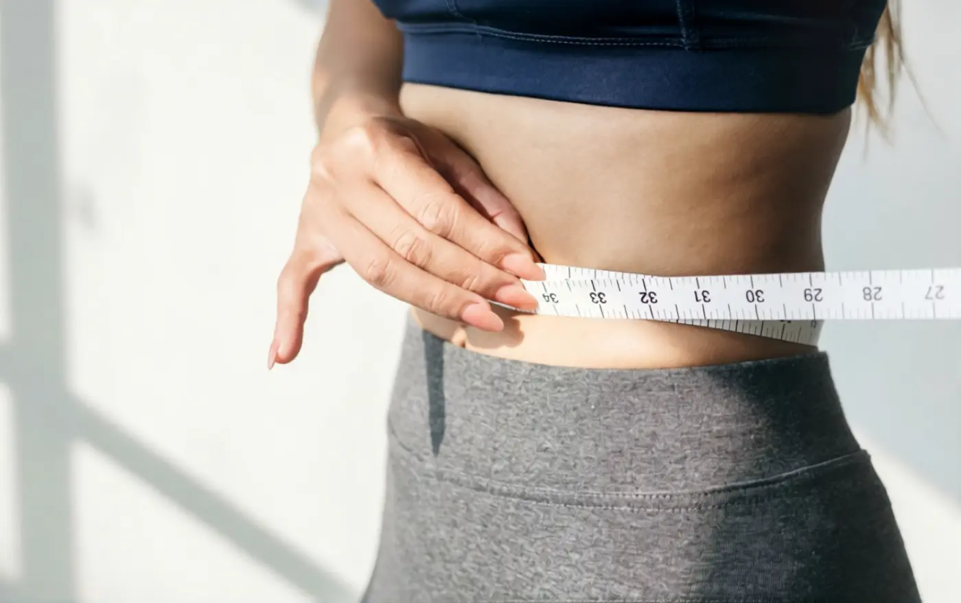 Person measuring waist as part of a metabolic wellness routine